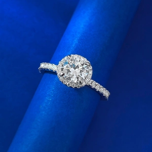Macro shot of 1 carat round diamond ring with halo setting on blue display stand