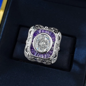 Macro detail of oval carbon diamond ring with purple baguette halo in blue velvet gift box