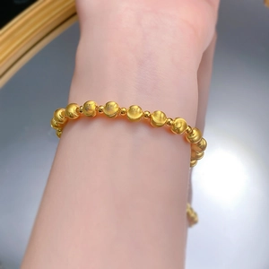 Macro view of gold beaded bracelet with brushed texture and minimalist laser-cut design