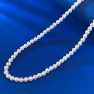 Collier en argent S925 avec perles blanches brillantes posé sur un fond bleu éclatant