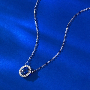 Gros plan d'un collier en argent 925 avec pendentif corindon bleu ovale et halo de diamants