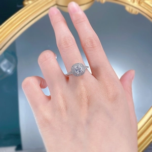 Close-up of a cushion-cut halo ring with a split shank on a hand with golden decor