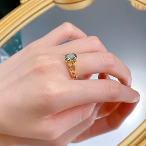 Detail view of gold ring with oval green stone and star cutouts on the band