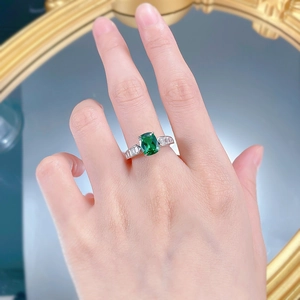 Detail of S925 silver ring with rectangular emerald gemstone on model hand