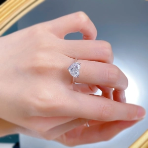 Gros plan d'une bague avec diamant en forme de cœur au doigt montrant l'éclat et l'anneau S925
