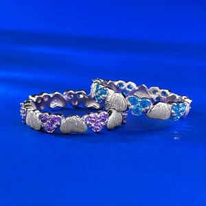 Detail of vintage brushed silver rings featuring interconnected heart shapes and blue gems