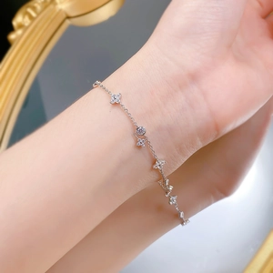 Détail d'un bracelet en argent S925 avec breloques florales et un cristal central brillant