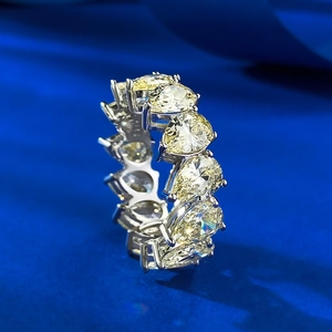 Macro shot of eternity ring featuring pear-cut yellow gemstones on blue fabric
