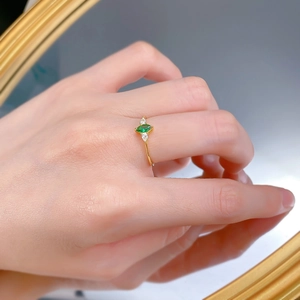 Close-up of a marquise cut emerald ring with side stones worn on a finger