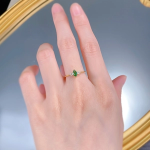 Detail of marquise-cut emerald ring worn on finger with elegant golden band finish