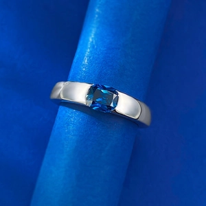 Macro shot of silver ring featuring a rectangular deep blue gemstone on a blue stand