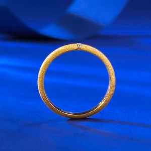 Macro detail of gold brushed ring with small diamond and inner metal hallmark