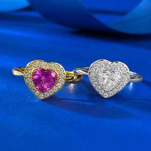 Macro detail of heart-cut pink and white crystal rings with halo setting on blue silk