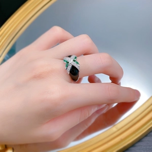 Detail of S925 silver ring featuring X-shape design with green gems and black enamel