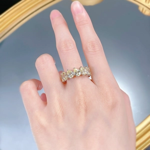 Close-up of five pear-cut yellow gemstones set in a silver eternity ring on a hand