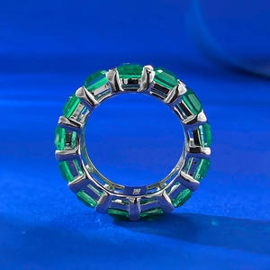 Macro shot of 925 sterling silver band with emerald-cut green gemstones in claw setting