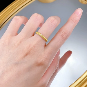 Close-up of slim gold ring with brushed texture and tiny diamond accent on finger