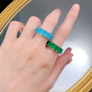 Close-up of 925 silver rings featuring emerald-cut blue and green gemstones on finger