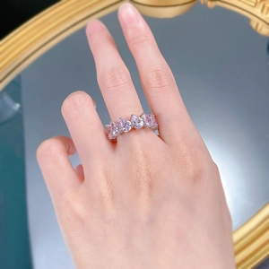 Macro detail of pear-cut pink stones paved on a silver-tone band ring worn on hand