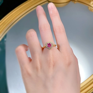 Detail of a heart-shaped pink gemstone ring with halo diamond setting on a woman's finger