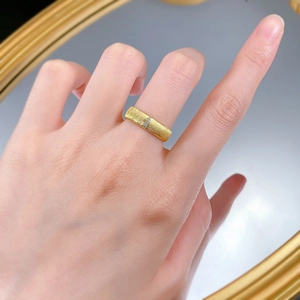 Macro detail of gold-tone brushed finish ring featuring micro-pave diamond accents