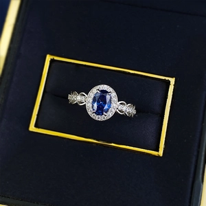 Elegant halo ring featuring oval blue sapphire and intricate silver wave band details