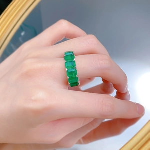 Close-up of silver ring with rectangular emerald-cut green gemstones on finger