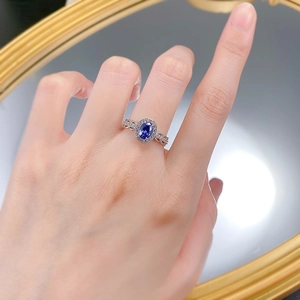 Detailed macro view of an oval blue sapphire ring with intricate hollow floral patterns