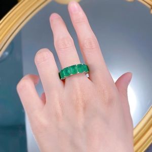 Detail view of emerald cut green gemstones set in a silver eternity band on a model