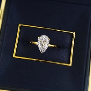 Gros plan d'une bague en argent en forme de poire dorée dans un écrin en velours
