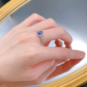 Detailed view of an oval blue sapphire ring with hollow chain band on model finger