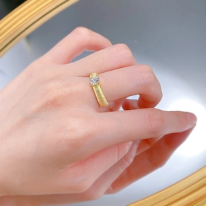 Detail of gold-plated S925 silver ring with brushed texture and sparkling round solitaire diamond