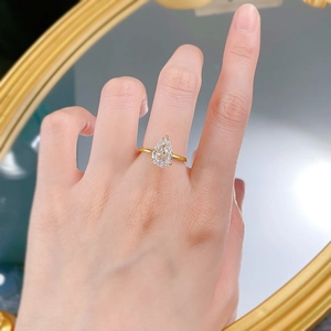 Gros plan d'une bague goutte avec pierre taille poire et monture griffes plaquée or