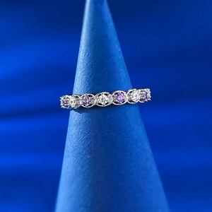 Macro d'une bague en argent S925 avec zircons blancs et violets sur support bleu