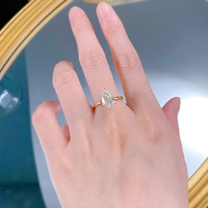 Vue macro d'une bague halo poire avec anneau doré portée dans un cadre luxueux