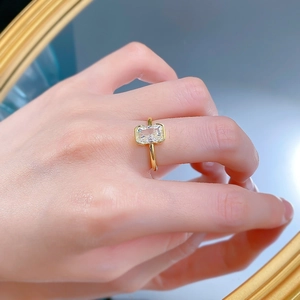Dettaglio anello dorato con zircone bianco taglio radiant su superficie a specchio