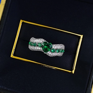 Elegant silver heart-shaped emerald ring with accent stones in a black velvet jewelry box