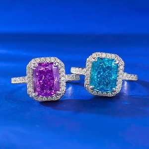 Radiant cut purple and blue carbon diamond engagement rings on a velvet blue surface