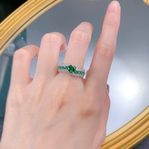 Silver ring featuring heart-cut green emerald center stone with pavé-set side crystals