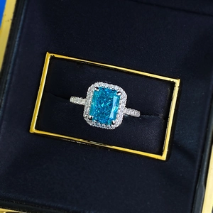 Macro shot of rectangular blue crystal ring with halo pavé setting in a luxury box