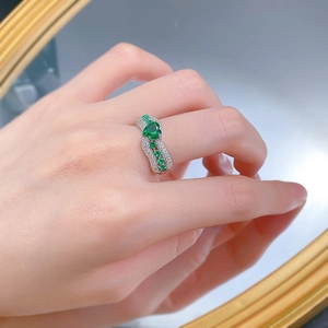 Close-up of heart-shaped emerald ring with pavé diamonds on a model's hand