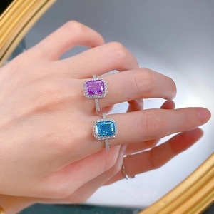 Detail of Radiant cut halo rings in light purple and sea blue on model's hand