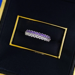Macro shot of silver ring with parallel rows of purple and white round gemstones