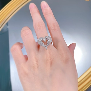 Macro detail of a sparkling silver heart ring with pavé-set diamonds on a finger