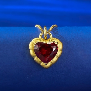 Macro shot of large heart-cut garnet pendant set in frosted gold with detailed wave edges