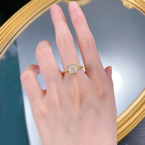 Detailed view of square radiant cut gemstone ring with gold plated band on finger