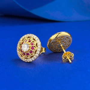 Macro shot of gold floral stud earring featuring ruby and diamond-like stones in vintage style