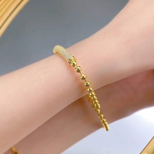 Detailed close-up of a gold-plated beaded bracelet with a sparkling crystal pave section