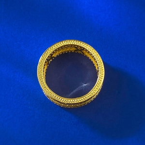 Vue détaillée d'une bague dorée vintage avec bords tressés et motifs évidés en forme de X