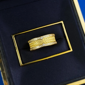 Détail de la bague tressée dorée avec bordures en zircone dans un écrin bleu luxe